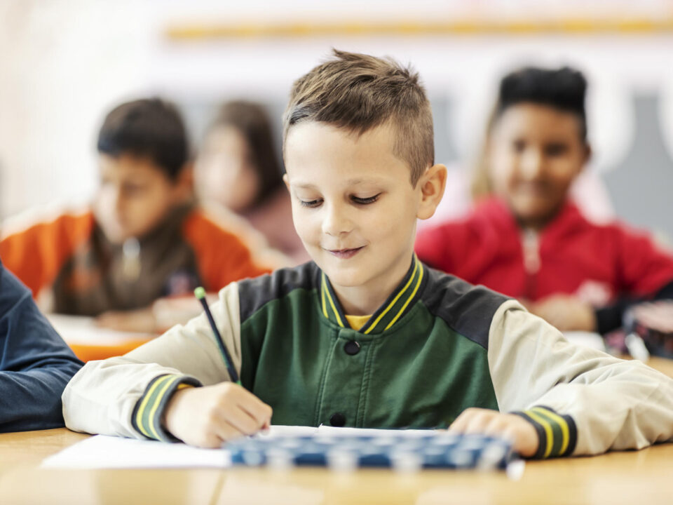 A happy boy learning new things on class in school.