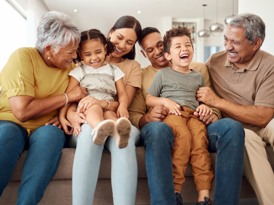 Happy, big family and quality time bonding of children, parents and grandparents together on a sofa. Laughing kids having fun with mom, dad and grandparent on a home living room couch with happiness