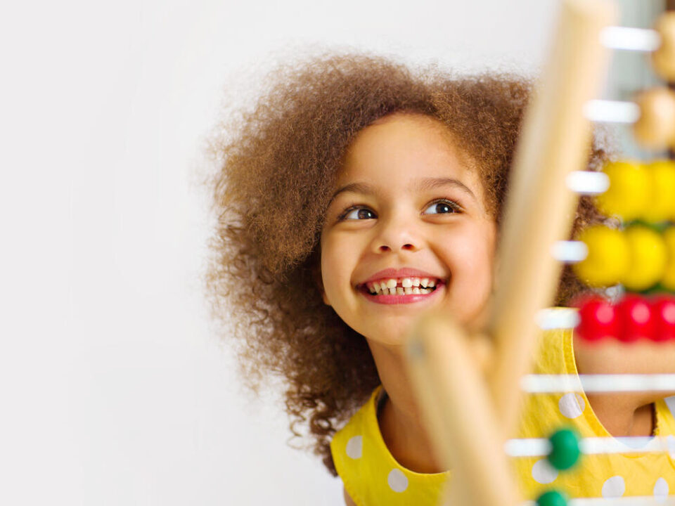 A dark skinned African American girl is ready for a math and arithmetic lesson with an abacus.