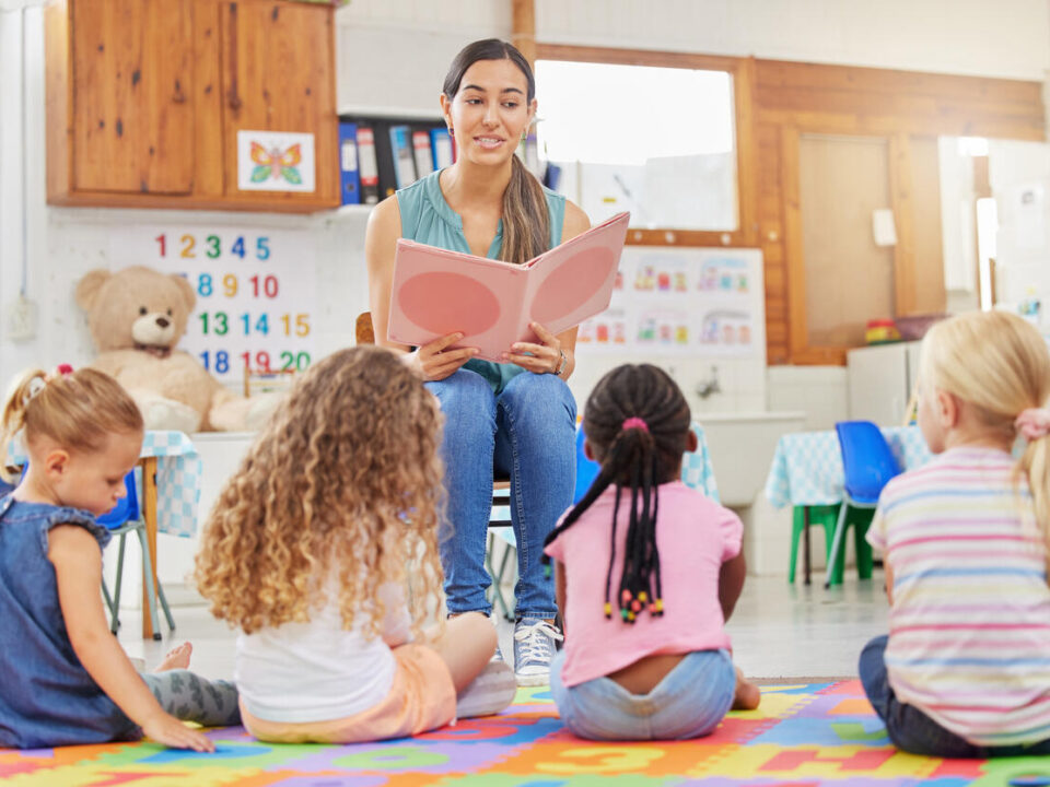 Shot of a young woman reading to her preschool students